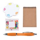 Sticky notes shaped like a flower, a small spiral-bound notebook, a pack of colorful jelly beans, and an orange pen arranged on a white background.