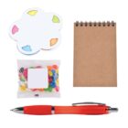 A set of office supplies and snacks includes a brown spiral notepad, a red pen, sticky notes shaped like a paint palette with colored tabs, and a small bag of colorful jelly beans.