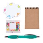 A small spiral notebook, a clear packet of colorful jelly beans, a teal pen, and a palette-shaped sticky notes pad with colorful tabs. Items are laid out on a white background.
