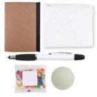 A flat lay of office items: a brown notebook, a white zip pouch, a pen with black and silver accents, a small bag of colorful jelly beans, and a round sticky note pad.