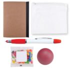 A flat lay of office items: a brown notebook with a black spine, a white zippered pouch, a red and white pen, a small clear bag of colorful jelly beans, and a red stress ball.