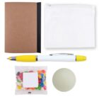 A flat lay image showing a brown notebook, a white zip pouch, a pen with yellow accents, a small bag of colorful jelly beans, and a round beige item on a white background.