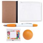 A kit featuring a brown notebook, a transparent zippered pouch, an orange and white pen, a pack of colorful jelly beans, and an orange stress ball.