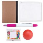 A flat lay image featuring a brown notebook with a black spine, a white zippered pouch, a white and pink pen, a small red stress ball, and a packet of colorful jellybeans with a blank label.