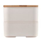 A minimalist, stackable bento lunch box with two compartments, featuring a smooth, off-white finish and a bamboo lid on top. Its compact design is suitable for portable meal storage.