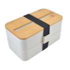A two-tiered, rectangular bento box with a wooden lid and a black elastic band around it. The box is cream-colored with smooth, rounded edges.