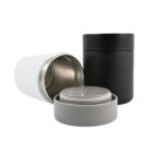Two cylindrical containers, one black and one white, are shown. The white container is open, revealing its metallic interior and a gray lid placed beside it. The black container behind is closed.