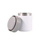 A white insulated food jar with a detachable gray lid placed beside it. The jar has a stainless steel rim at the top, and the lid has a smooth, round design. The background is a plain white.