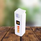 A white, rectangular, reusable lighter with the Real Electricity logo on the side, featuring a large R and the company name below it. It rests on a wooden surface with a blurred green background.