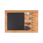 A wooden cheese board set with four metal cheese knives. The knives have wooden handles and are arranged on the right side of the board. The board has a square black slate surface on the left.