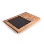 A wooden cutting board with a black slate inset, featuring three cheese knives with wooden handles placed on top.
