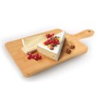 A wooden cutting board holds wedge and rectangular pieces of brie cheese garnished with red currants, walnuts, and rosemary.