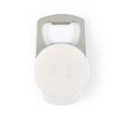 A silver bottle opener with a circular, blank white label in the center. The opener has a cutout at the top for opening bottle caps and a smooth, metallic finish.