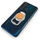 A dark blue smartphone with a circular wooden and silver phone grip attached to the back. The grip functions as both a stand and a bottle opener. The phone has multiple rear cameras and a fingerprint sensor.