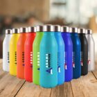 A row of colorful reusable water bottles on a wooden surface, featuring different vibrant shades such as white, yellow, orange, red, green, light blue, royal blue, navy, black, and gray. Each bottle has a logo and is set against a blurred background.