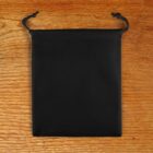 A small black drawstring pouch placed on a wooden surface.