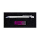 A ballpoint pen with a transparent lower half and silver accents is placed horizontally above a purple and black USB flash drive on a black textured surface.
