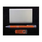 Set against a black background, the image shows a silver power bank, an orange pen with silver accents, and an orange and silver USB flash drive.