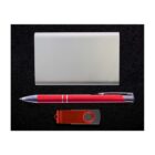 A silver cardholder placed above a red and silver pen, and a red USB drive with a swivel cover, all arranged neatly on a black textured surface.