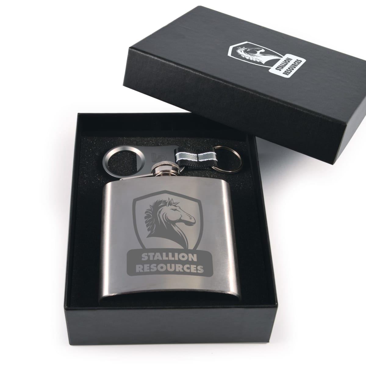 A stainless steel flask with a horse logo and Stallion Resources text is displayed inside an open black box. The box also contains a keychain and a steel clip, all set against a white background.