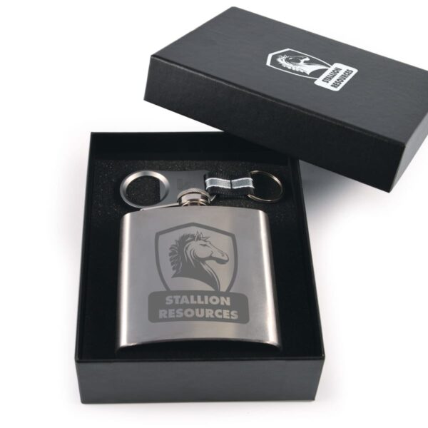A silver flask with Stallion Resources logo inside a black box. The box also contains a keychain and a funnel. The flask and box have matching logos depicting a horse framed by a shield.