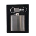 A stainless steel hip flask and a metal bottle opener keychain set in a black box. The flask is rectangular with rounded edges and a screw cap. The keychain has an oval cut-out for opening bottles.