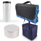 A white travel mug, a round white portable speaker, a folded blue checkered blanket with a black strap, and a navy blue insulated tote bag are displayed on a white background.