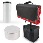 A travel set including a white travel mug, a cylindrical white speaker, and a black picnic blanket with red plaid edges, neatly attached to a black cooler bag with handles.