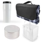 A collection of items including a white travel mug with a black lid, a silver portable speaker, a rolled-up black and white checkered blanket with a black cover, and a white insulated cooler bag with a handle.