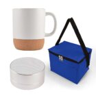A white ceramic mug with a cork base, a portable silver speaker, and a blue insulated cooler bag with black handles and a zipper.