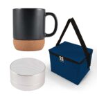 A matte black mug with a cork base, a small silver portable speaker, and a blue insulated lunch bag with a black strap and zipper, displayed on a white background.