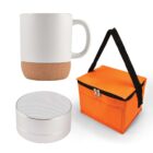 A white mug with a cork base, a small round silver speaker, and an orange insulated lunch bag with black handles and a zipper are displayed against a white background.