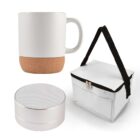 White ceramic mug with a cork base, a small silver Bluetooth speaker, and a white insulated lunch bag with a black strap are displayed against a plain background.