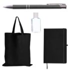 A black pen, a small bottle of clear hand sanitizer, a black tote bag, and a black notebook with a ribbon bookmark are arranged on a white background.