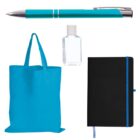 A blue pen, a small clear hand sanitizer bottle, a black notebook with a blue ribbon, and a blue tote bag are arranged against a white background.