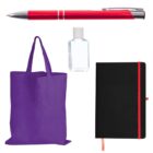 A red pen, a small bottle of clear sanitizer, a black notebook with a red elastic band, and a purple tote bag are arranged against a white background.