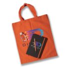 Orange tote bag with a colorful logo, a small bottle of hand sanitizer, a black notebook with the same logo, and a pen placed on the notebook.