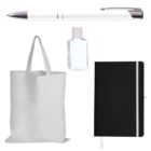 A collection of promotional items, including a white and silver pen, a small clear bottle of hand sanitizer, a plain white tote bag, and a black notebook with a white elastic band and bookmark.