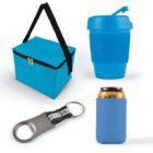 A blue insulated lunch bag with black strap, a blue reusable travel cup with lid, a metal bottle opener with a black strap, and a blue can cooler sleeve are arranged on a white surface.