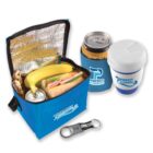 A blue lunch bag with the Perfect Plumbing logo, containing a sandwich, banana, granola bar, and soda can. Nearby are a can cooler with a drink, a reusable cup with a lid, and a bottle opener keychain.