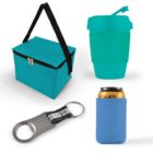 A collection of turquoise promotional items: a teal insulated lunch bag with a black strap and zipper, a teal reusable cup with a lid, a silver and black bottle opener keychain, and a blue can cooler sleeve holding a can.