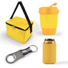 A yellow insulated lunch bag with black handles, a yellow reusable coffee cup with a lid, a red and silver bottle opener with a keyring, and a yellow can cooler holding a beverage can.