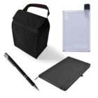 A black lunch bag, a clear flat water bottle with a black lid, a black pen with silver accents, and a closed black notebook with an elastic band are arranged against a white background.