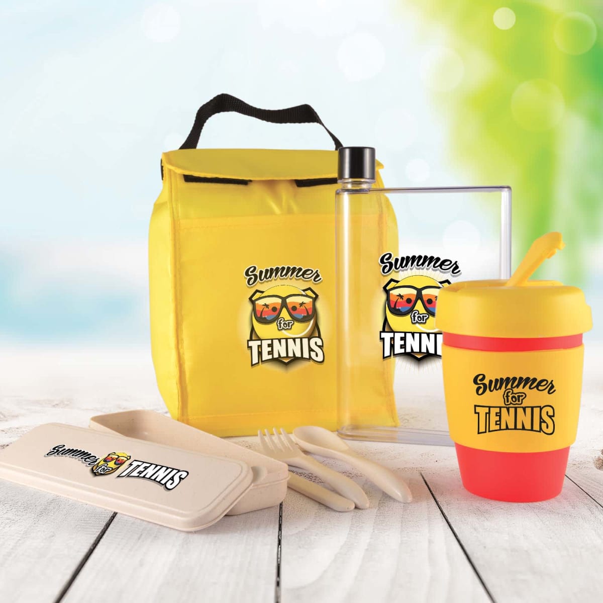A collection of summer-themed tennis merchandise, including a yellow lunch bag, transparent drink bottle, pink and yellow cup with lid, utensil set in a box, all featuring the Summer for Tennis logo with sunglasses and sun illustrations.