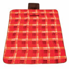 A red and orange checkered picnic blanket with a plaid pattern lies flat. Theres a built-in brown flap pillow at the top for head support. The blanket has a visible black border around the edges.