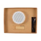 Portable speaker in cardboard box with USB cable and wooden accessory.