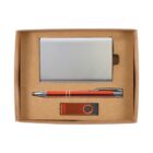 A gift box containing a silver metal cardholder, an orange and silver pen, and an orange USB drive with a silver swivel cover, all neatly arranged on a brown base.