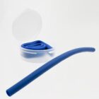 A flexible blue silicone straw partially unrolled next to its transparent circular carrying case. The case is open, revealing the folded straw inside against a neutral white background.