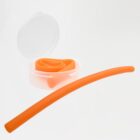 An orange wax earplug partially unrolled next to a small open round case with more of the same colored earplug inside. The background is plain white.