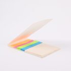 An open notebook with colorful sticky tabs in pink, yellow, green, and blue on a white background. The notebook cover is partially open, showing the tabs neatly lined up inside.